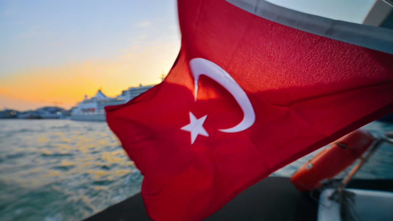 Türkiye, İstanbul'da gün batımında, Boğaz'da yüzen bir teknede dalgalanan Türk bayrağı. Ağır çekim