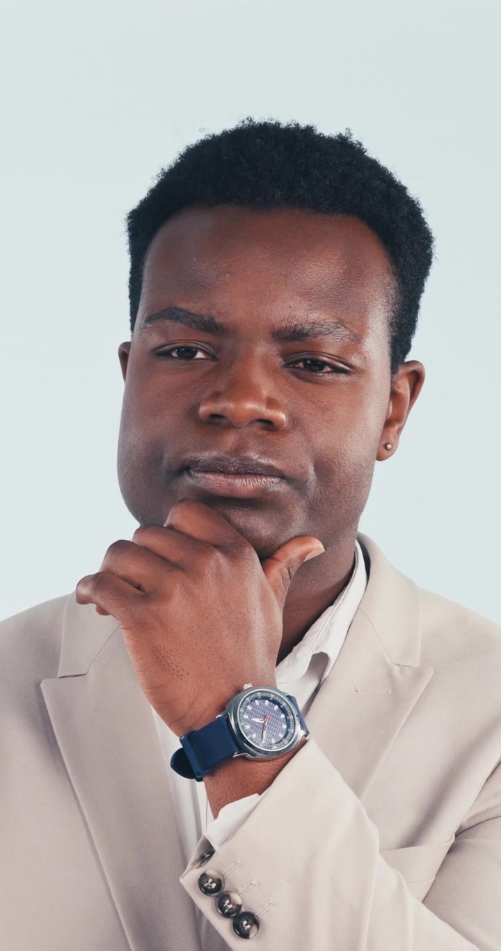 Thoughtful Young Man in Beige Suit Posing Against Plain Background