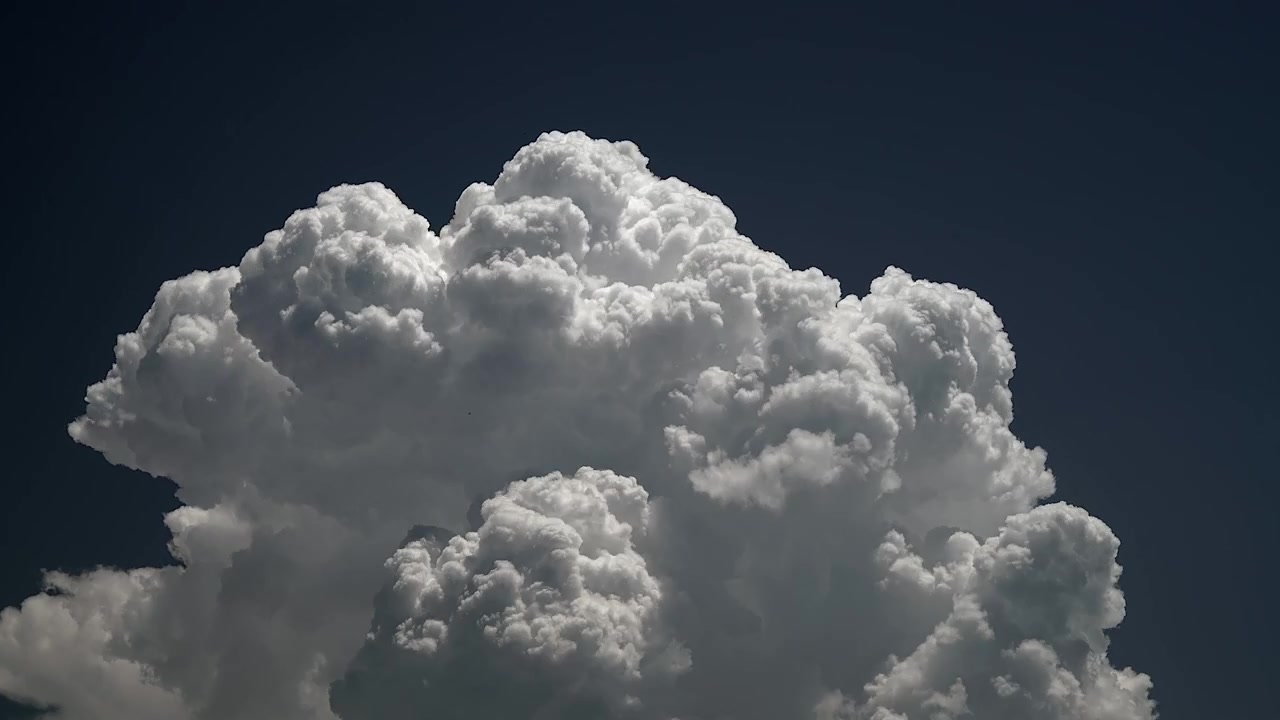 Time Lapse of Large White Cumulus Cloud Growing Against Dark Blue Sky
