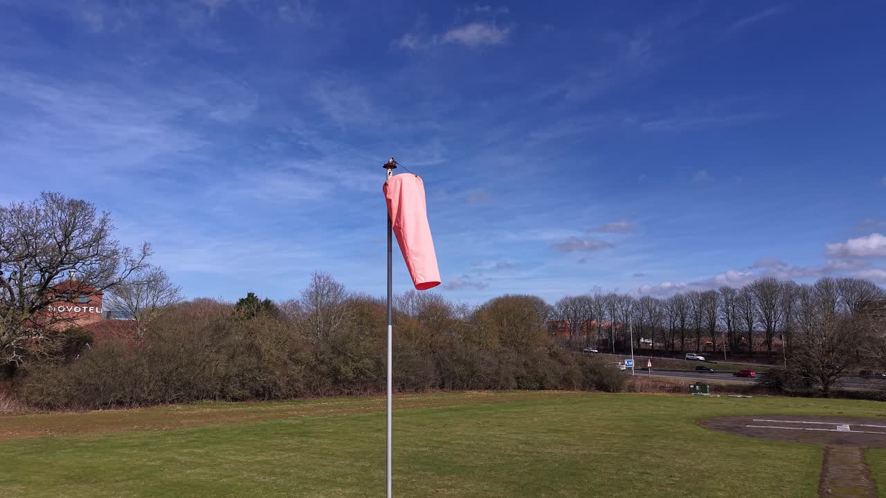 Fluorescent windsock blowing in the wind with a clear blue sky in the background