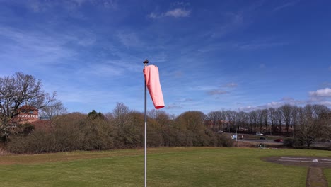 fluorescent windsock blowing in the wind with a clear blue sky in the background