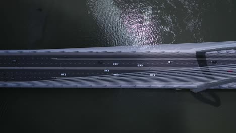 Top-down-aerial-view-of-suspension-bridge-over-river-with-road-traffic