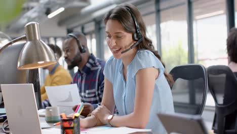 Portrait-of-happy-caucasian-businesswoman-talking-on-phone-headset-at-office