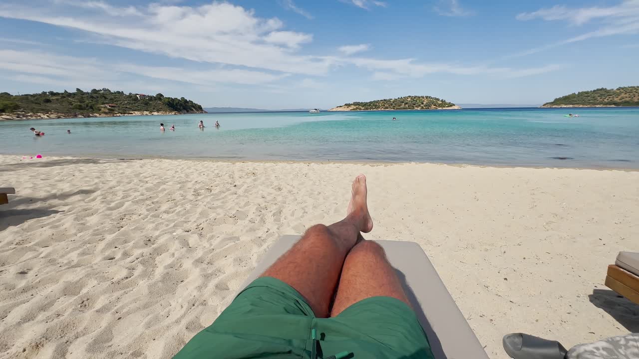 Man swimming and sunbathing on the clean blue flag beaches of Greece's Halkidiki Peninsula