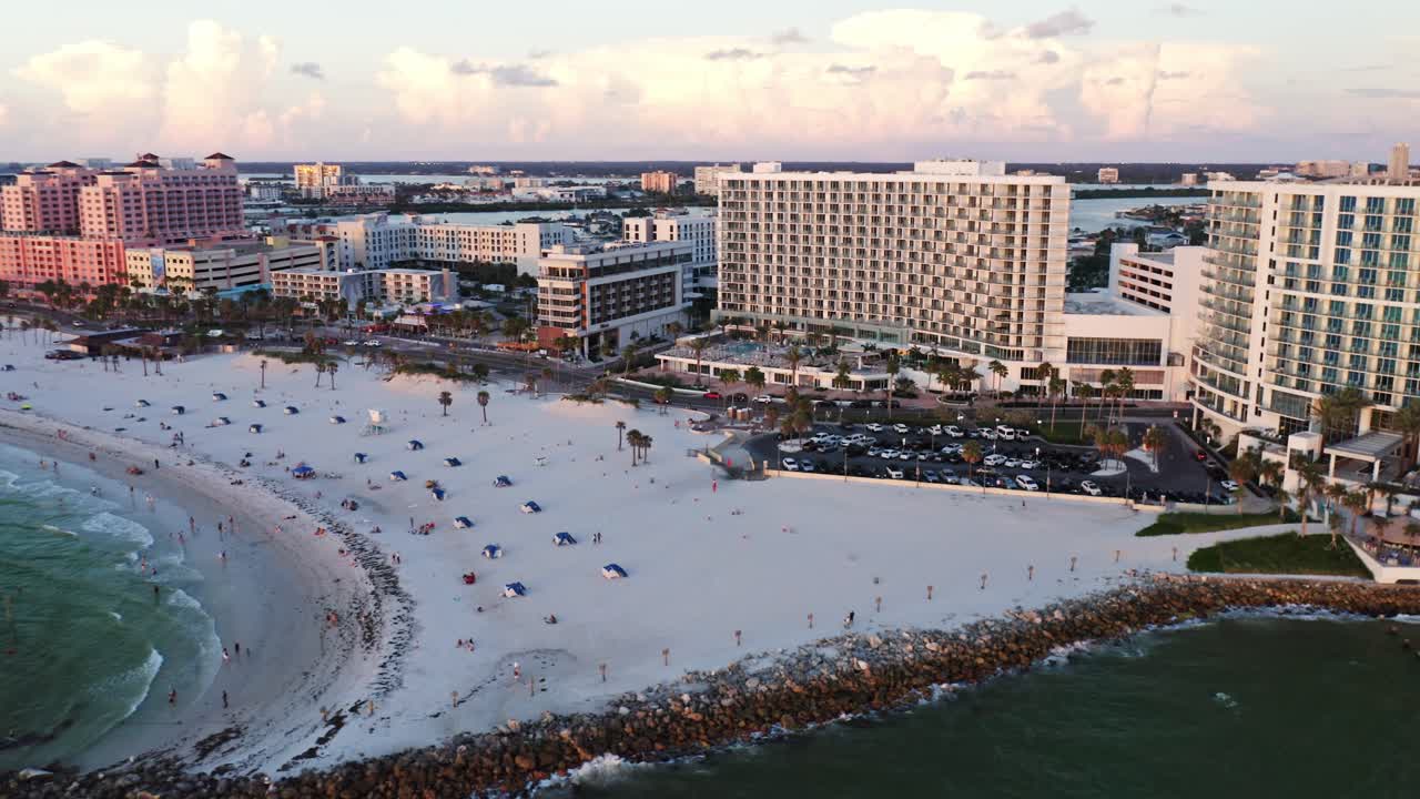 Resort di lusso costeggiano la riva di sabbia bianca di Clearwater Beach, con bagnanti, ombrelloni e le calme acque del Golfo che creano una vivace meta di vacanza costiera.