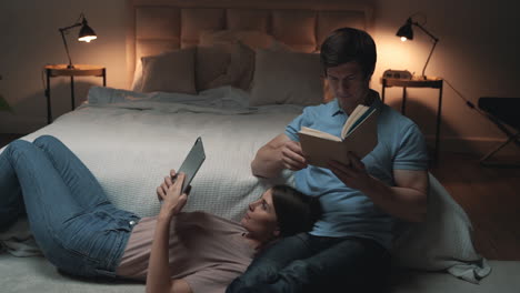 Pareja-Joven-Sentada-En-El-Dormitorio,-Mujer-Y-Hombre-Leyendo-Y-Relajándose,-Compartiendo-Momentos