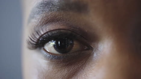 mujer afroamericana de cerca parpadeando el ojo mirando el reflejo de la cámara en el iris