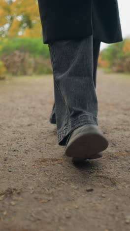primer plano de pies en movimiento vaqueros negros y zapatos de lona corriendo a través de un colorido jardín de otoño, capturando la esencia de un estilo de vida activo al aire libre en medio de un paisaje de otoño