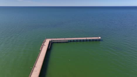 Aerial-view-a-bridge-standing-on-the-beach-of-Palanga,-which-goes-to-the-Baltic-Sea