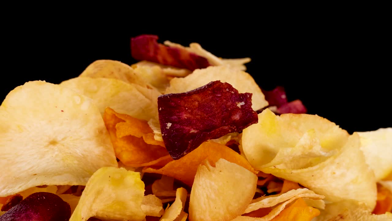 Assorted root vegetable chips in crisp detail, static camera, bright studio lighting, black background