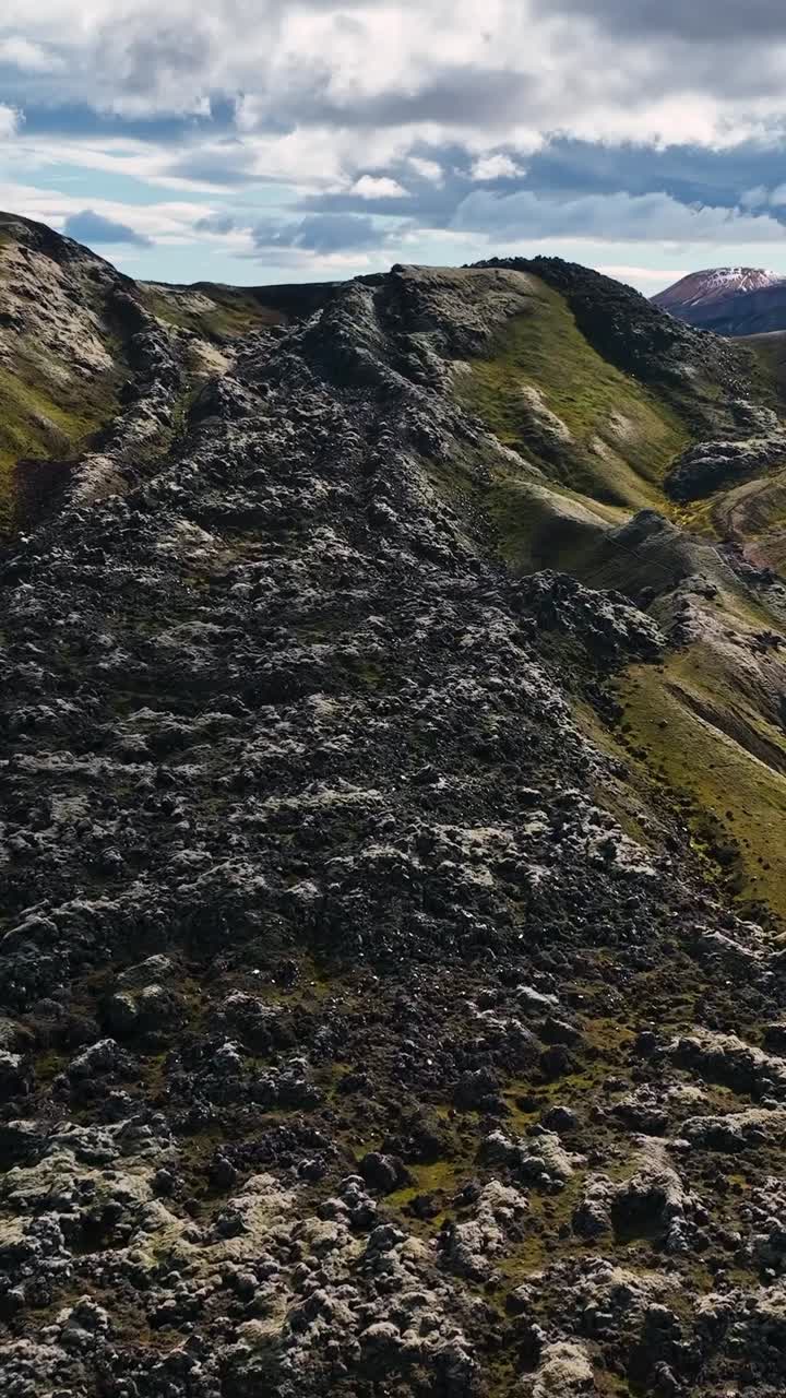 A vertical drone fly over view of lava flow - stream of molten rock, or magma, erupted from a volcano's vent creating mountain in Iceland