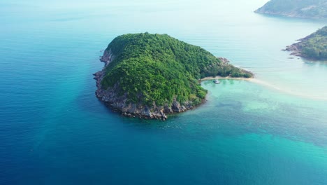 Thailand-islands,-aerial,-Green-cay-with-palms-and-rocky-coast-in-the-endless-aquamarine-ocean