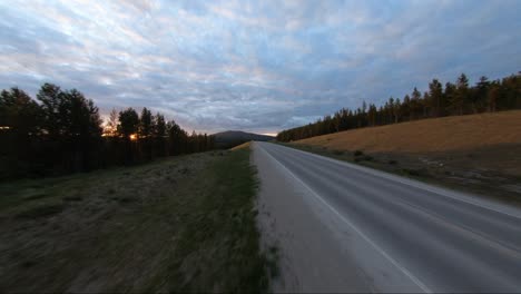 A-white-sports-car-drives-down-a-highway-during-an-amazing-colorful-sunset