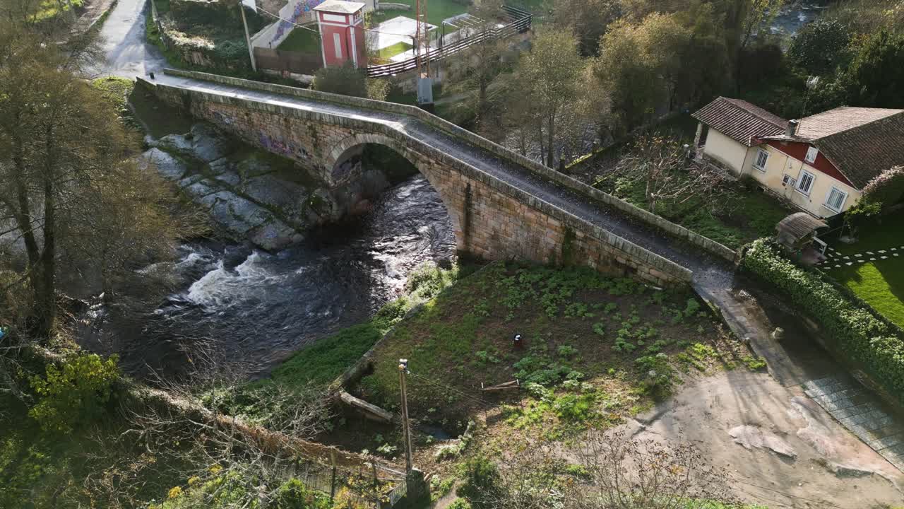 vista aérea estática de un puente angulado con una abertura circular redonda con aguas pesadas del río ionia fluyendo