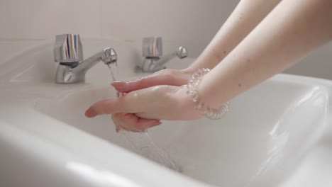 a young lady washing her hands in the bathroom sink