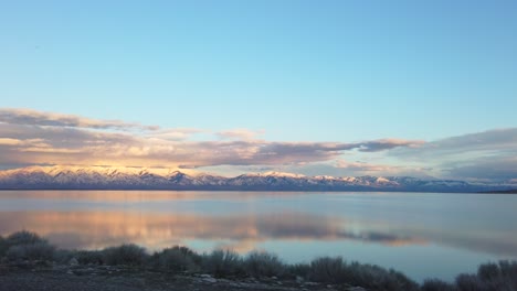 utah mountains mirrored on the lake as sun goes down and foreground wizzes by