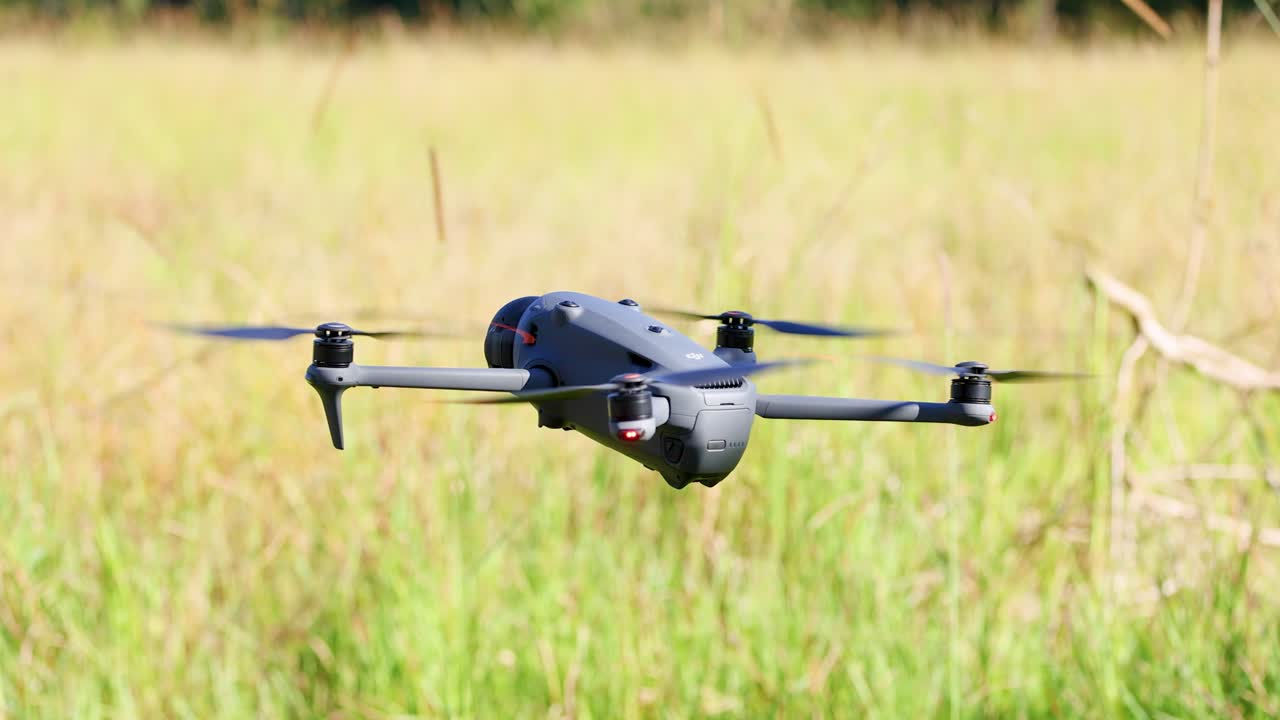 A drone hovers and rotates above a grassy field in Gold Coast, Australia, under bright daylight