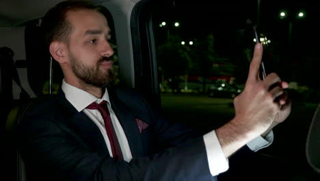 happy businessman taking a selfie in the back seat of his luxury car with personal driver