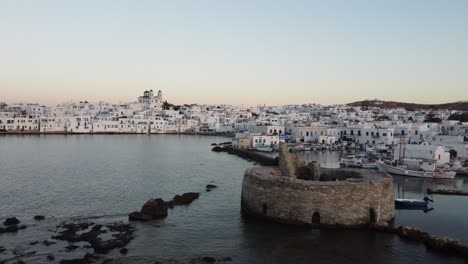 Paros,-Naoussa,-Greece-coastline-and-traditional-White-houses-during-sunset,-Aerial-view