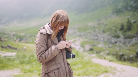 a young woman hiker climbs mountains with photo camera. transfagarasan, carpathian mountains in romania