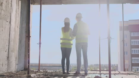 arquitecto y técnico de vuelta en el sitio de construcción revisando los planos de la oficina