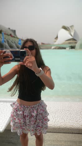 mujer tomando una selfie frente a una característica de agua arquitectónica moderna