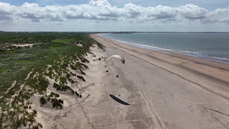 lonely paraglider soaring on netherlands coastline, aerial view