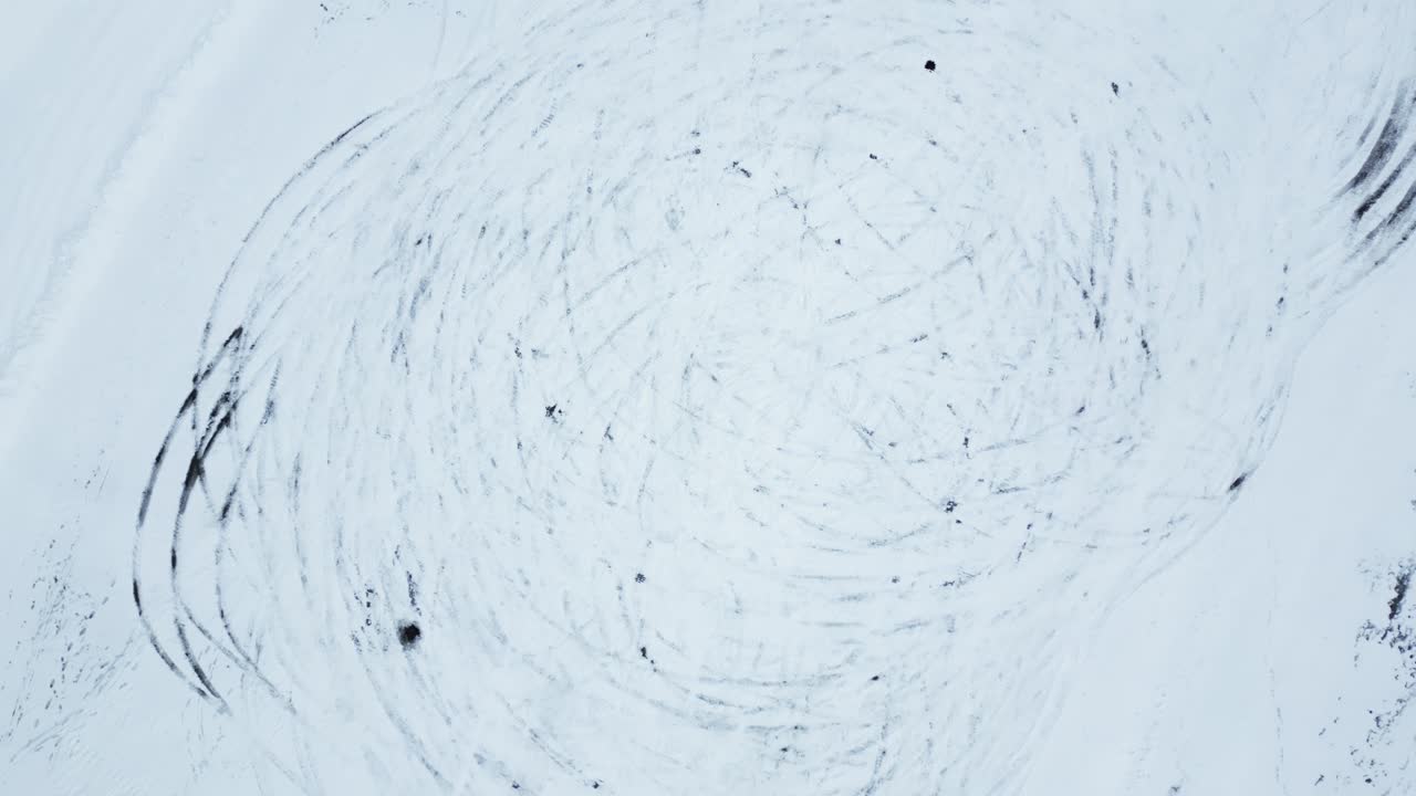 눈 속의 타이어 트랙, 도 패턴의 크리스 크로스, 빈 주차장에서 차가 회전하는 모습, 드론 상단 아래로