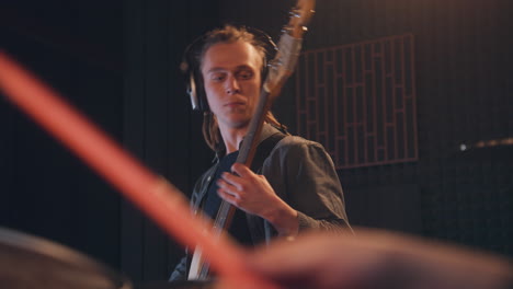 musical band records song in sound recording studio. male guitarist in headphones plays the electric guitar. close up of drummer playing a drum set. music recording room. music production concept.