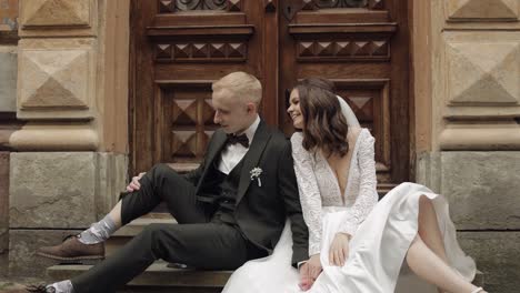 newlyweds love, caucasian groom with bride sitting, embracing, hugs in city street, wedding couple