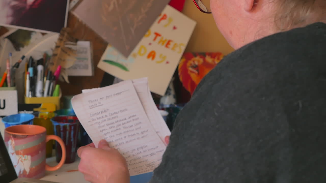 mujer que trabaja desde casa lee una nota escrita a mano, inclinada sobre el hombro