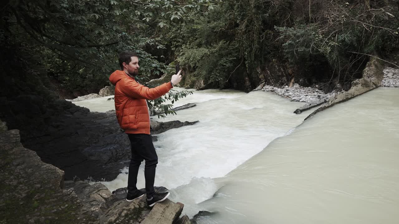 hombre tomando una foto de un río de montaña