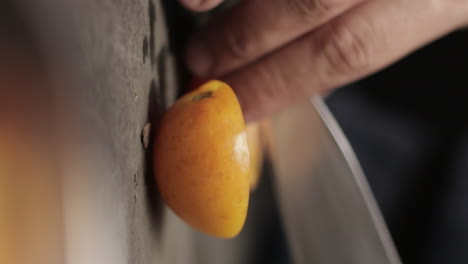 very close up shot on male hands cutting small yellow cherry tomato with sharp stainless steel knife