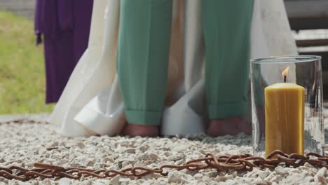 a barefoot bridal couple in a symbolic iron chain circle with a burning candle. neo-pagan ritual.