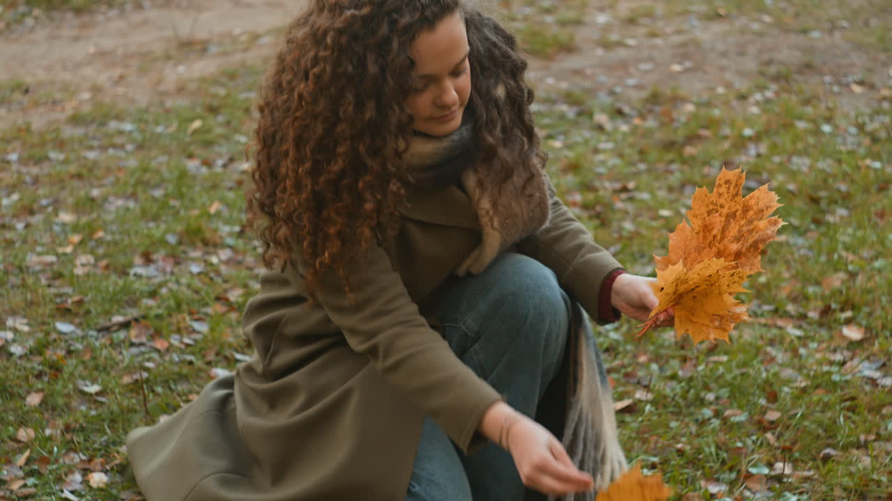 A young woman enjoying autumn leaves in a park
