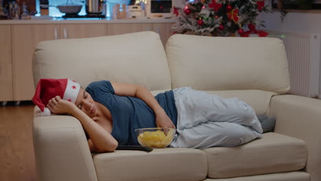 sleepy woman wearing santa hat and resting on couch