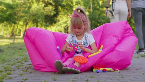 Niña-Alegre-Jugando,-Girando-Con-Un-Juguete-Antiestrés-Sensorial-Pop-It-En-El-Parque,-Alivio-Del-Estrés-Y-La-Ansiedad