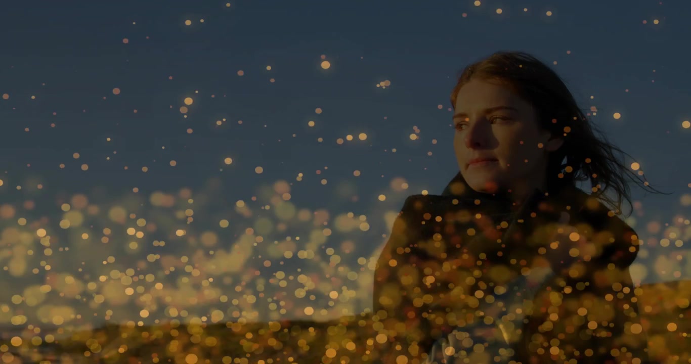 Mujer de pie en un paisaje crepuscular para una sesión de moda, con el viento moviendo su cabello, un bokeh dorado desplazándose y abriendo los ojos.