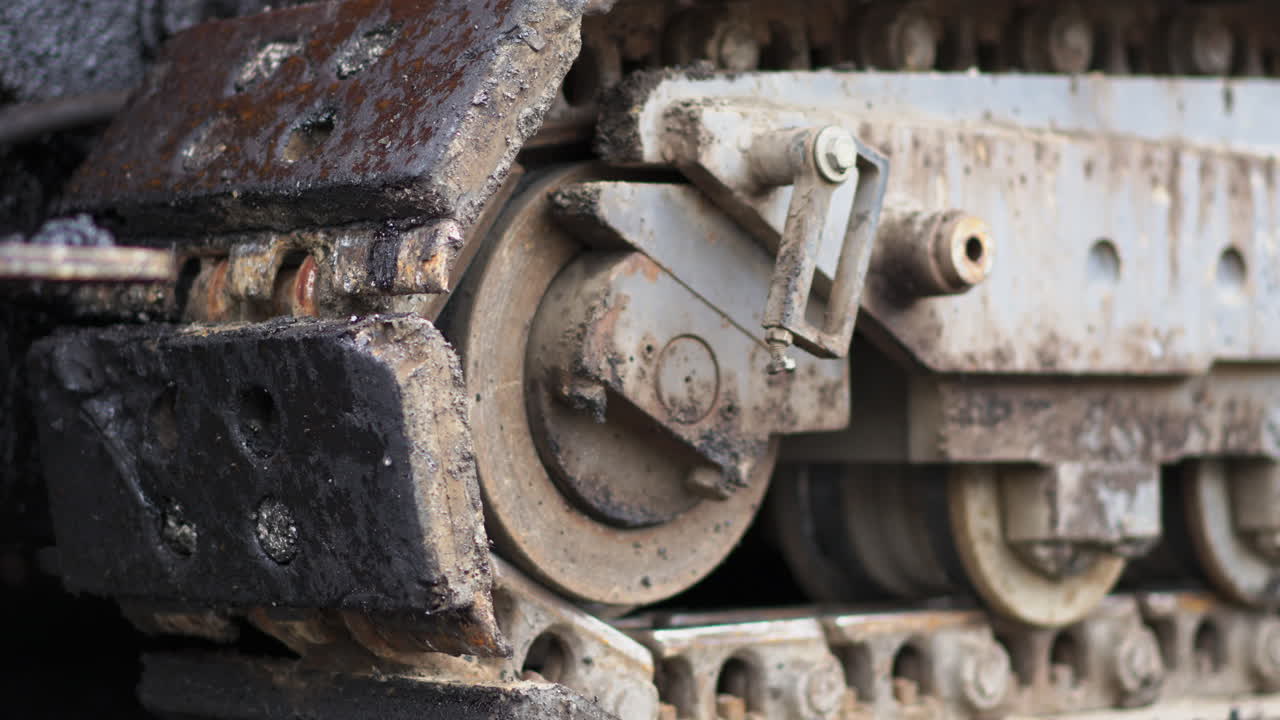 건설 현장의 신선한 새로운 도로에서 천천히 움직이는 아스팔트 트랙 페이버 트랙의 클로즈업 - 세부 사항