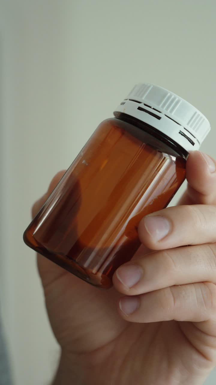 Primer plano de un frasco de medicina vacío en la mano, simbolizando el uso de medicamentos, la necesidad de reponer y la rutina de atención médica.