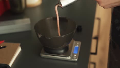 las manos del peluquero exprimiendo el tinte de un tubo en un cuenco en una escala