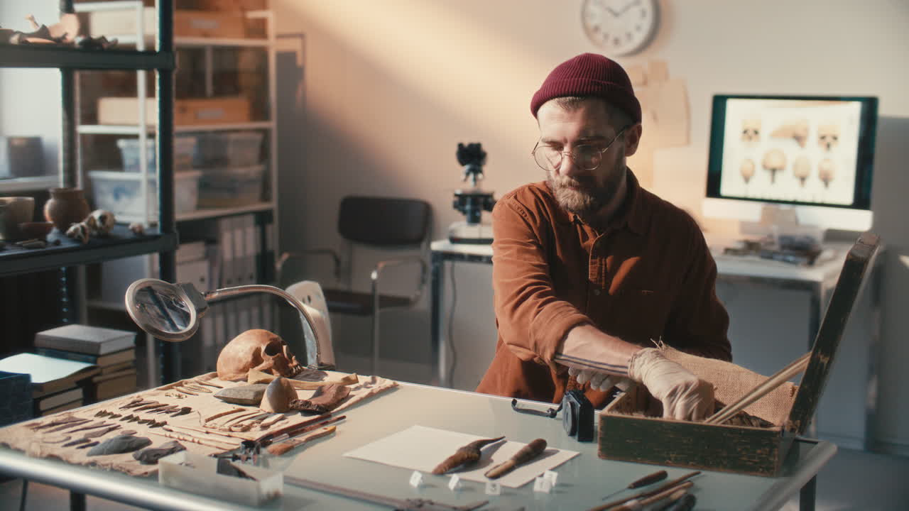 археолог, документирующий артефакты с помощью камеры на рабочем месте в лаборатории