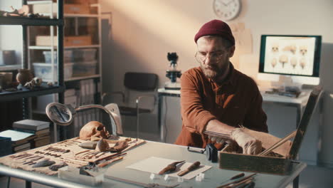 arqueólogo documentando artefactos con cámara en el lugar de trabajo en el laboratorio