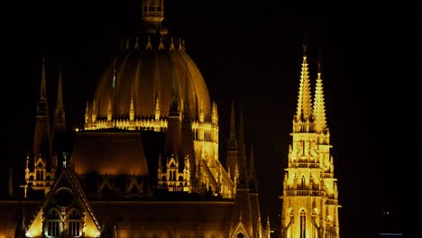 Budapest-city-center-view-with-Parliament-building-and-Danube-river-at-night,-gothic-architecture,-light-reflections,-medium-shot-with-towers