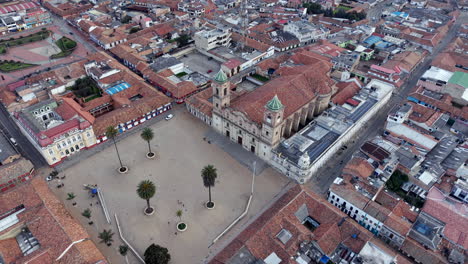 drone video shows the open expanse of plaza de los comuneros, zipaquira, framed by colonial architecture. the serene mood is enhanced by soft daylight outlining the vibrant rooftops