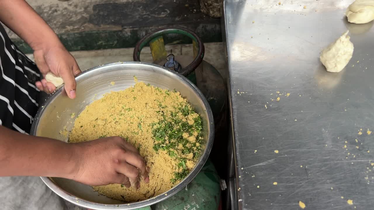 Close up shot of a man filling dal in puri for making kachori in Kolkata.