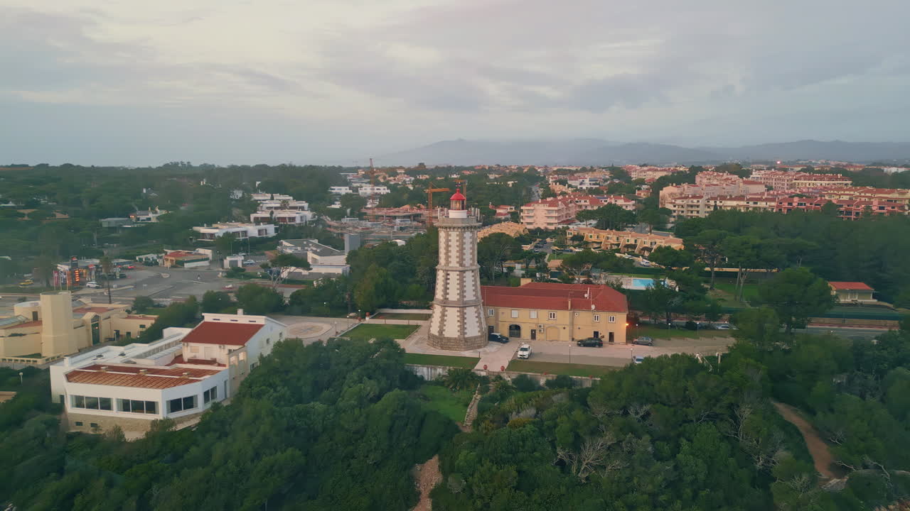 High lighthouse blinking cloudy evening sky drone shot. Modern beacon in town
