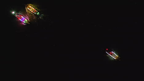4k aerial view of hoi an at night with illuminated streets, glowing boats and colorful lanterns along the river
