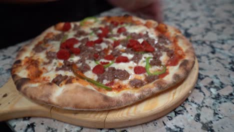 Italian-Pizza-with-Salami-and-paprika-being-cut