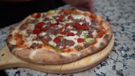 pizza italiana con salami y pimentón siendo cortada